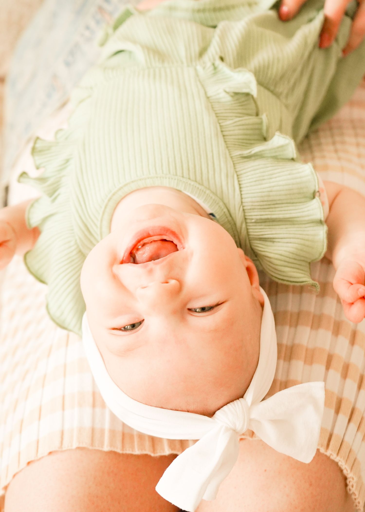 Close-up sequence of newborn baby wearing mint green bonnet and white bow.