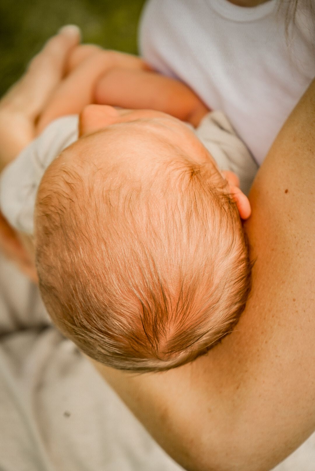 Delicate profile view of sleeping infant with wispy brown hair.