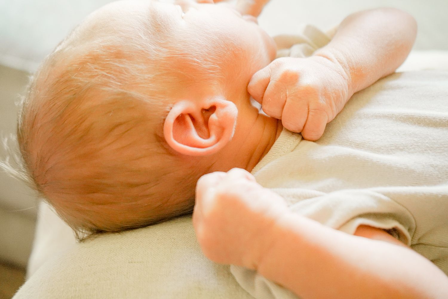 Close-up view of baby's feet and hands resting on white linens.