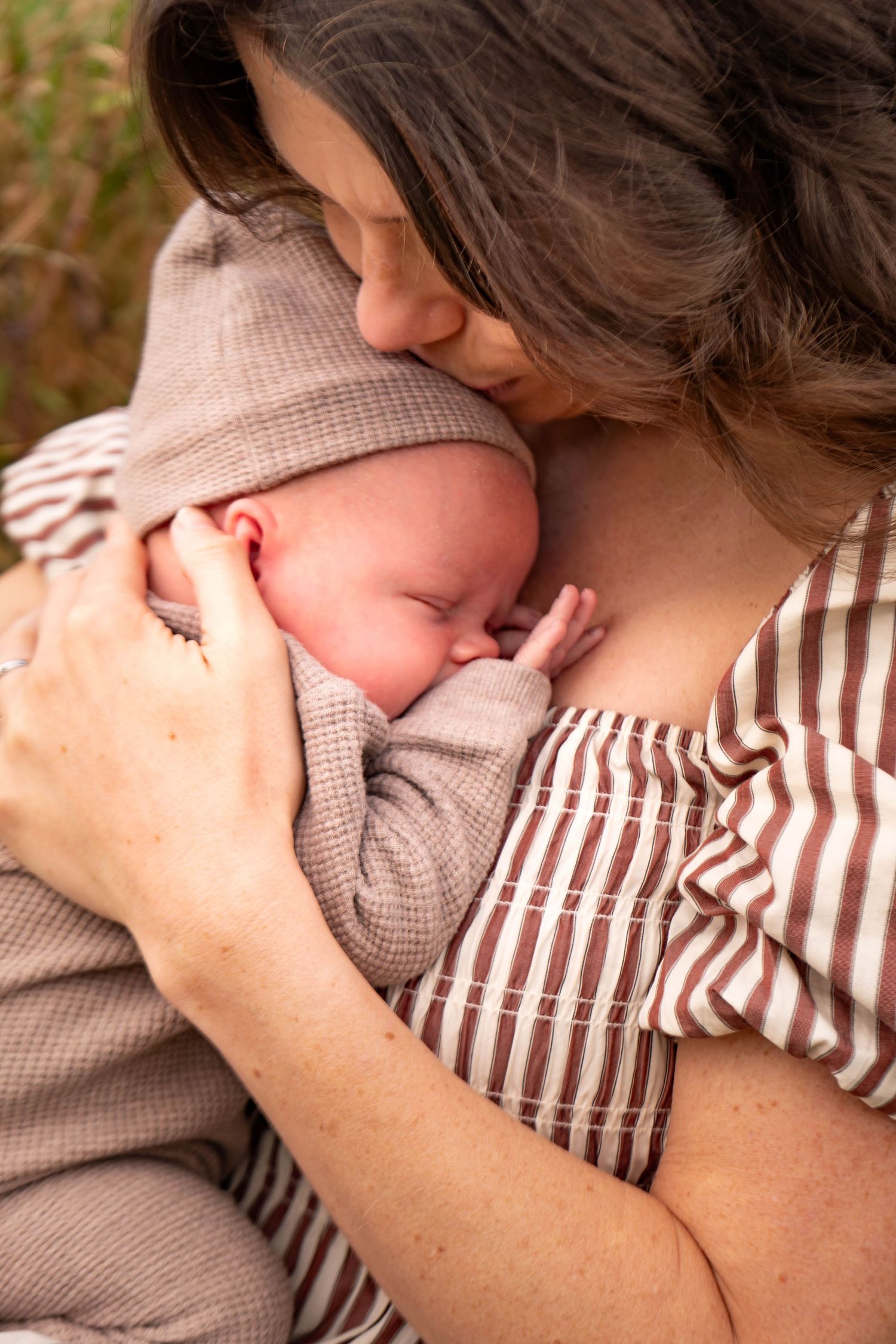 Intimate close-up of nurturing moment between parent and baby during outdoor photo session.