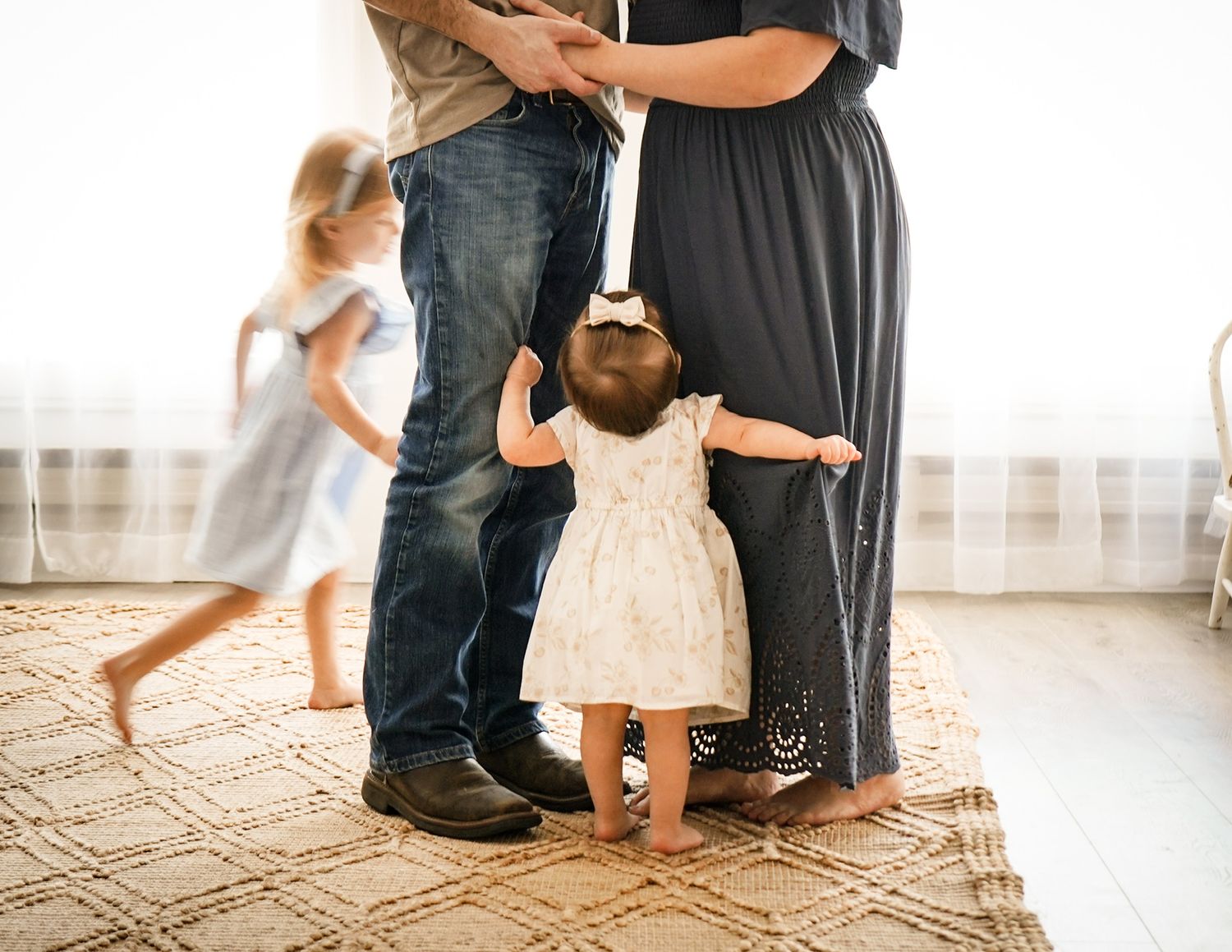 Cropped view of family members' legs and feet in casual setting indoors.