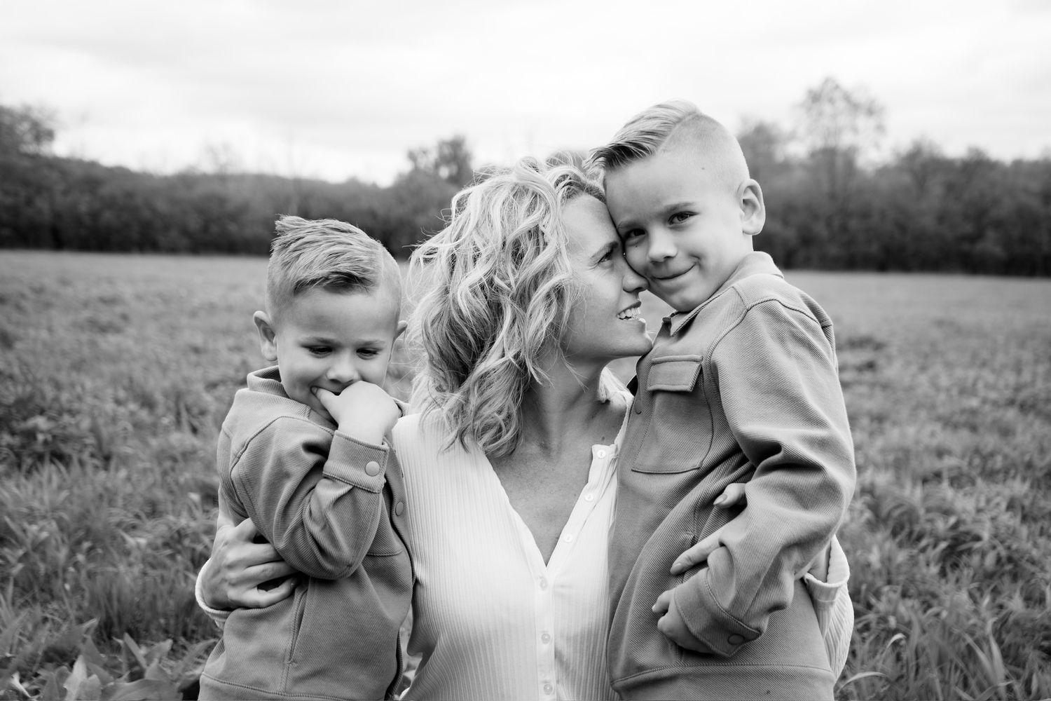 Black and white portrait of family members sharing intimate moments outdoors.