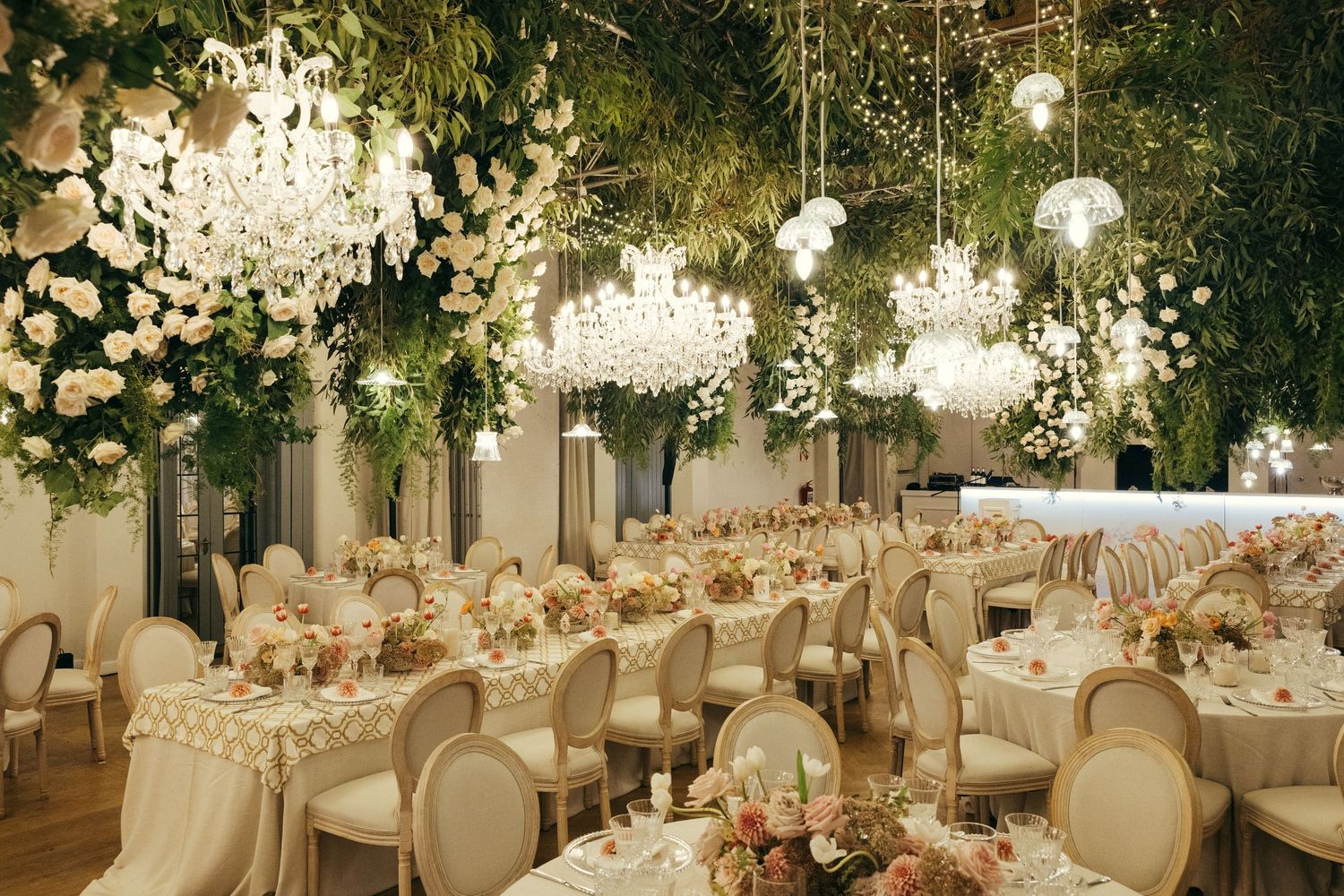 Elegant wedding reception venue with white floral arrangements and crystal chandeliers creating a romantic atmosphere.
