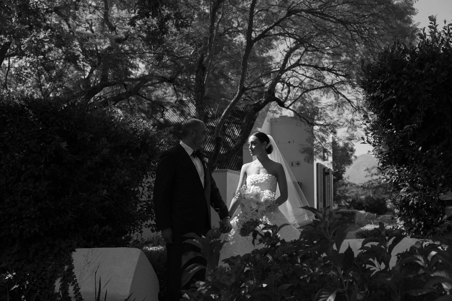Atmospheric black and white wedding portrait in garden setting.