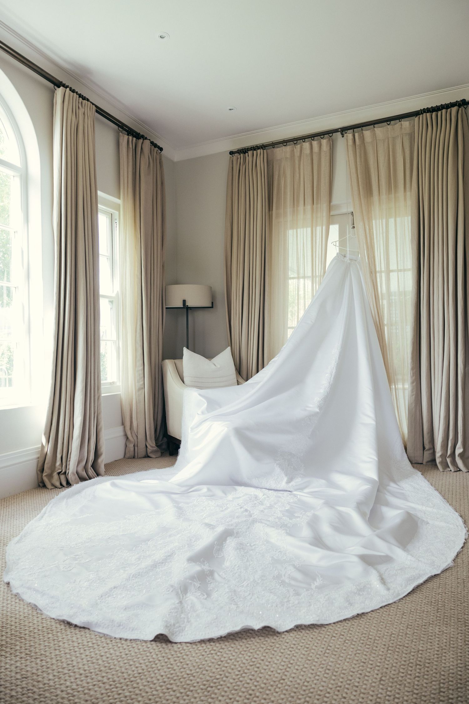 Dramatic full-length wedding gown with expansive train spread across carpeted room.