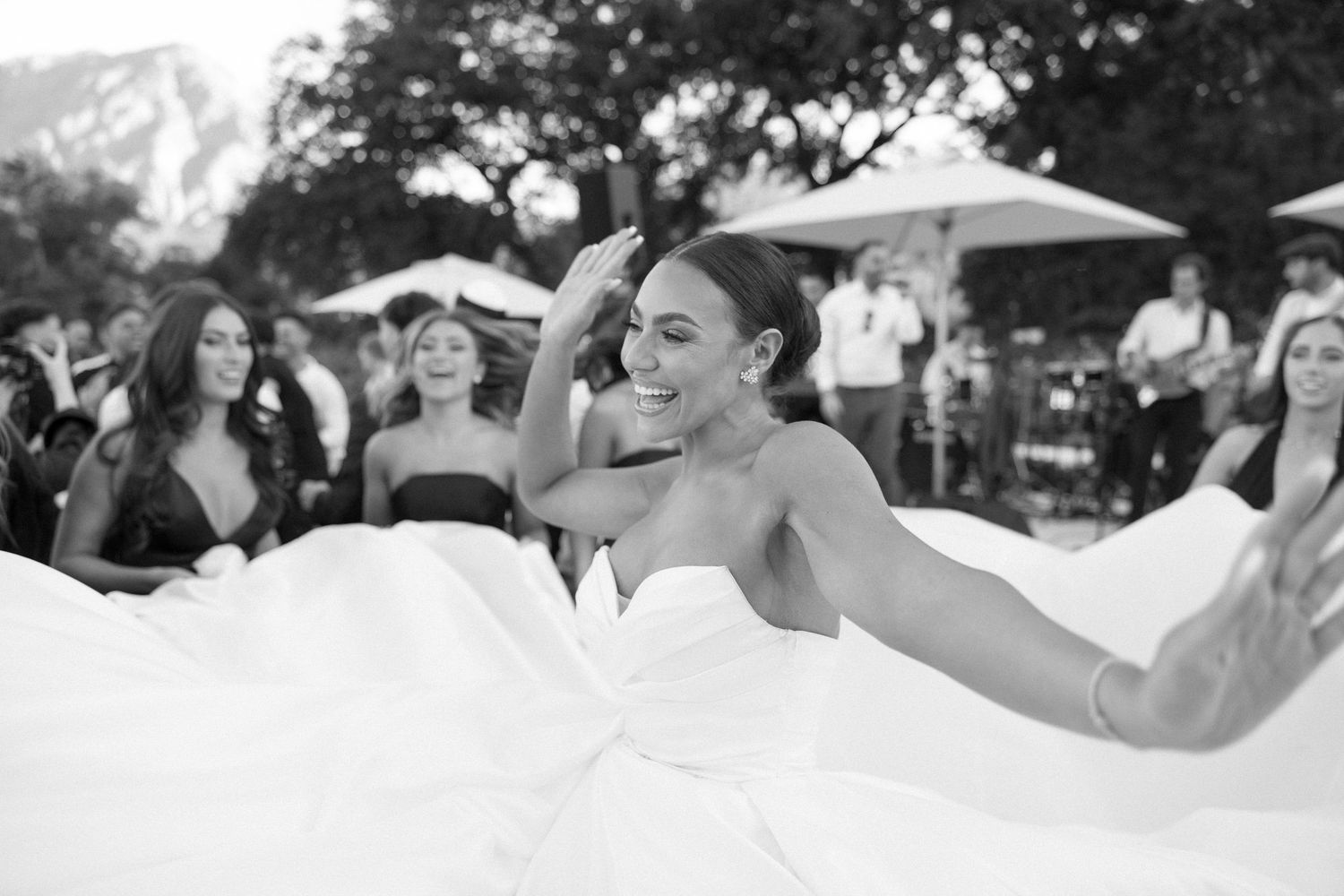 Black and white candid shot of joyful moments during an outdoor wedding celebration.