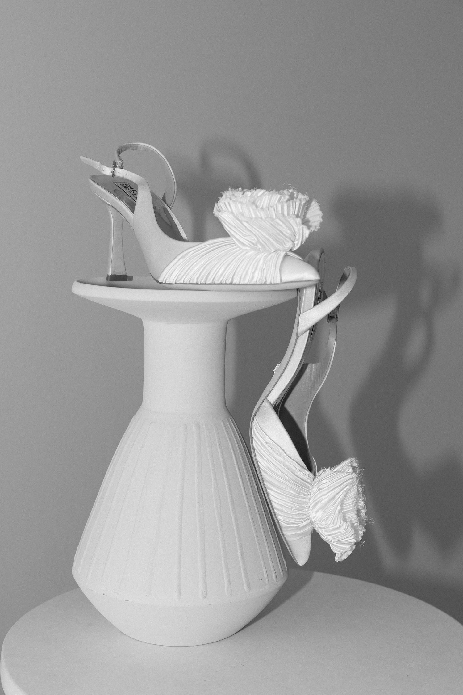 White ceramic teapot sculptures arranged in artistic progression on gray background.