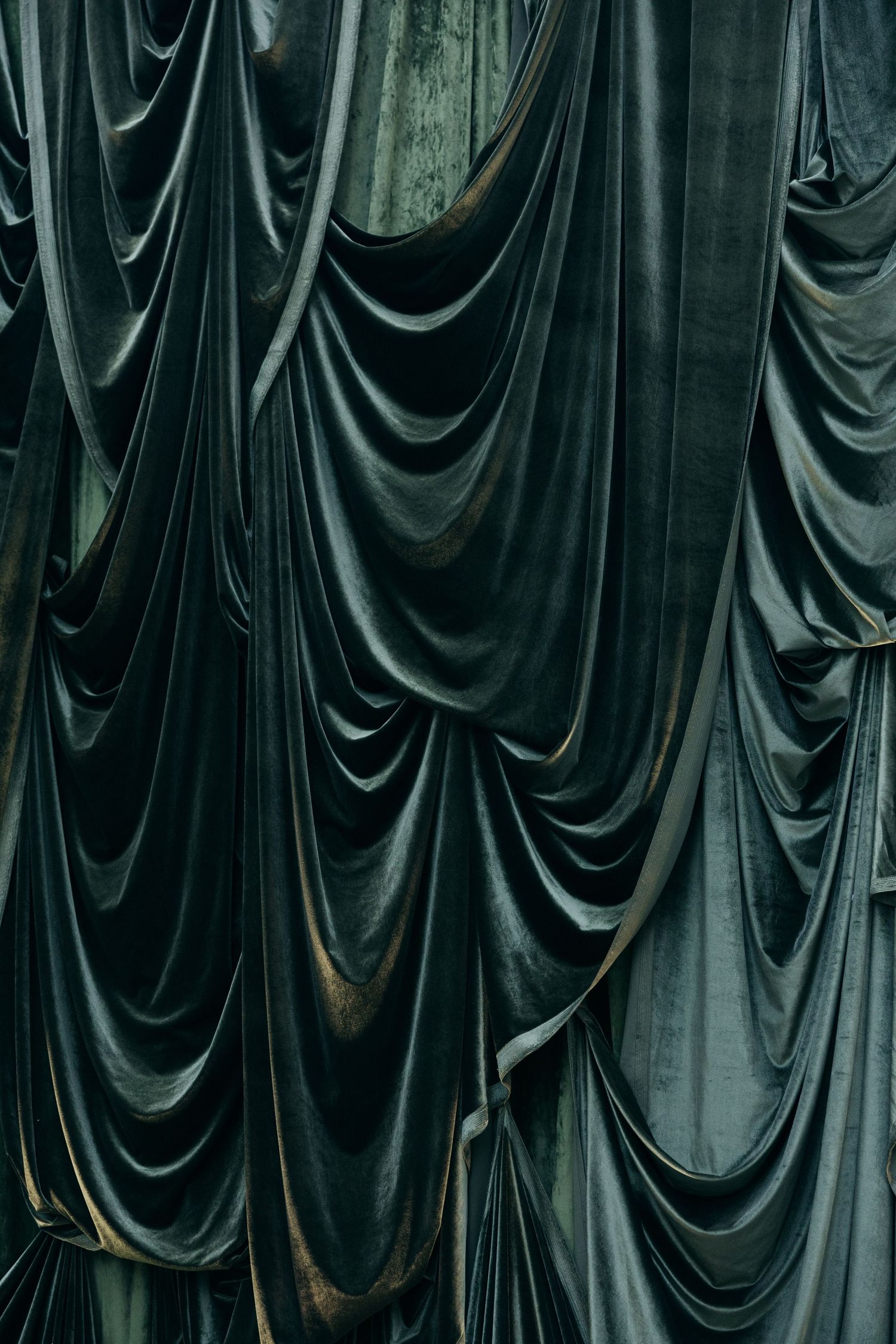 Abstract pattern of draped dark fabric creating elegant flowing curves and folds.