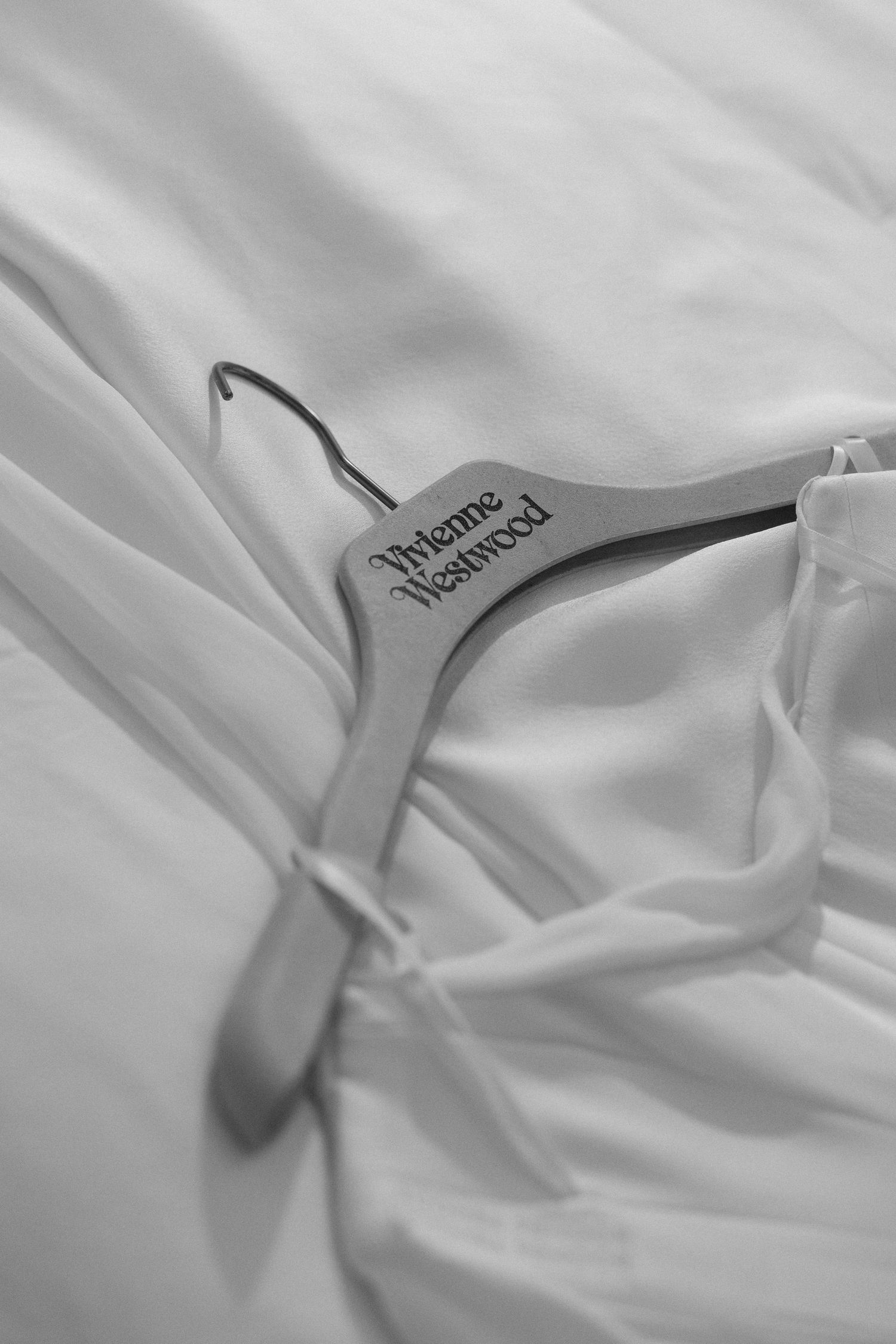 A close-up view of white clothing hangers on fabric backdrop creating an abstract minimalist composition.