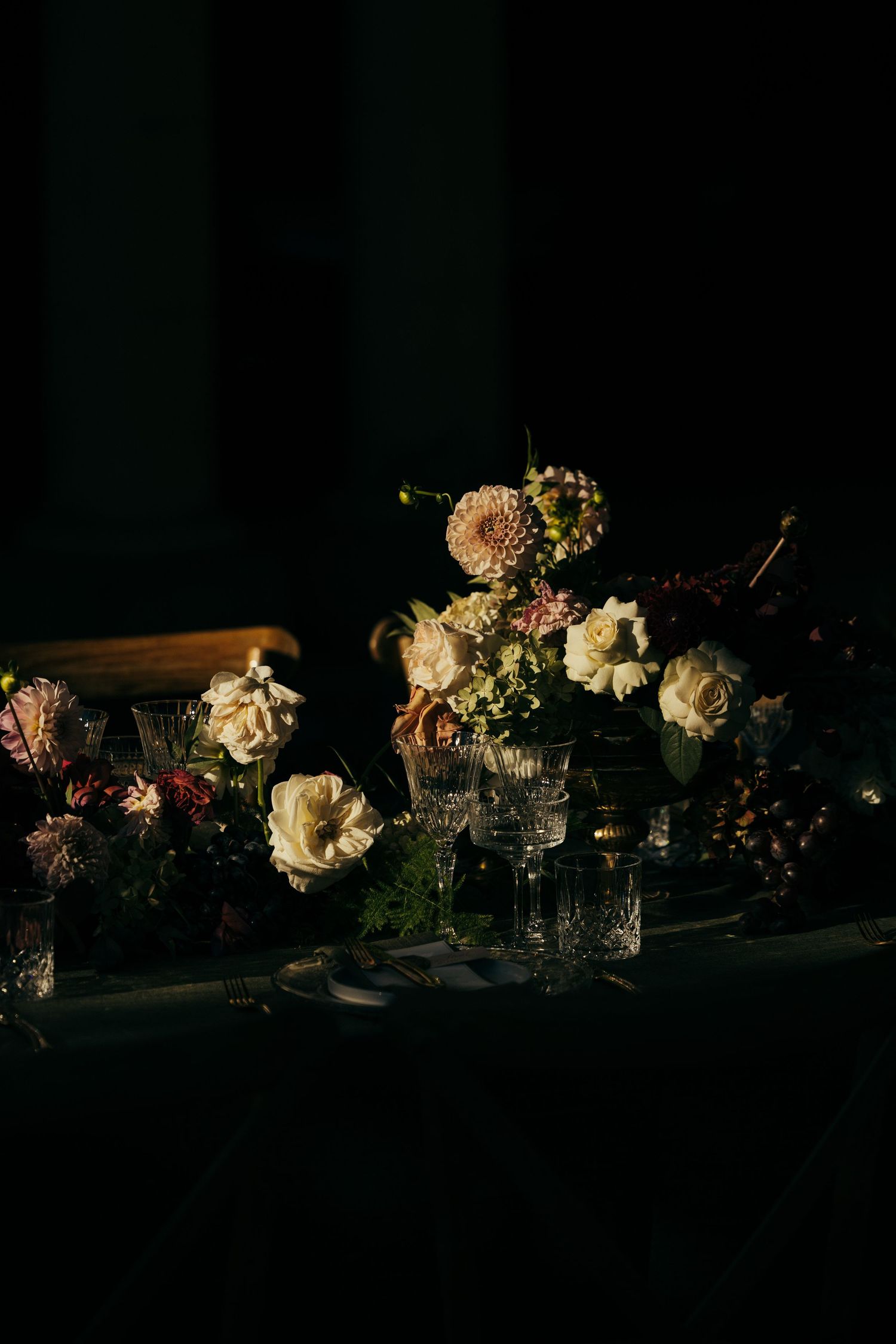 Low-light table decorations featuring white roses and candles in elegant glass vessels.