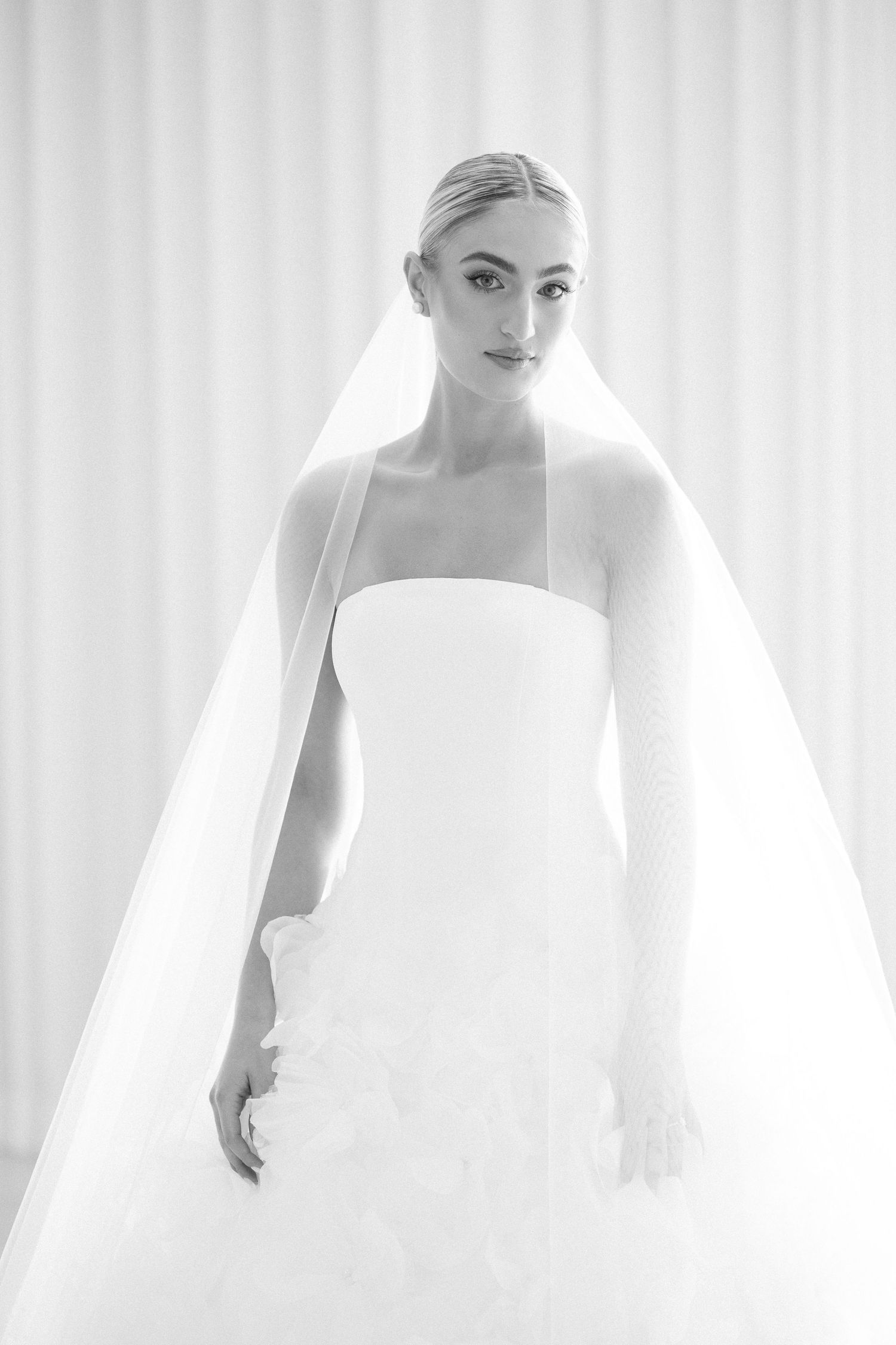 Ethereal bridal portrait series with flowing white veil against light background.