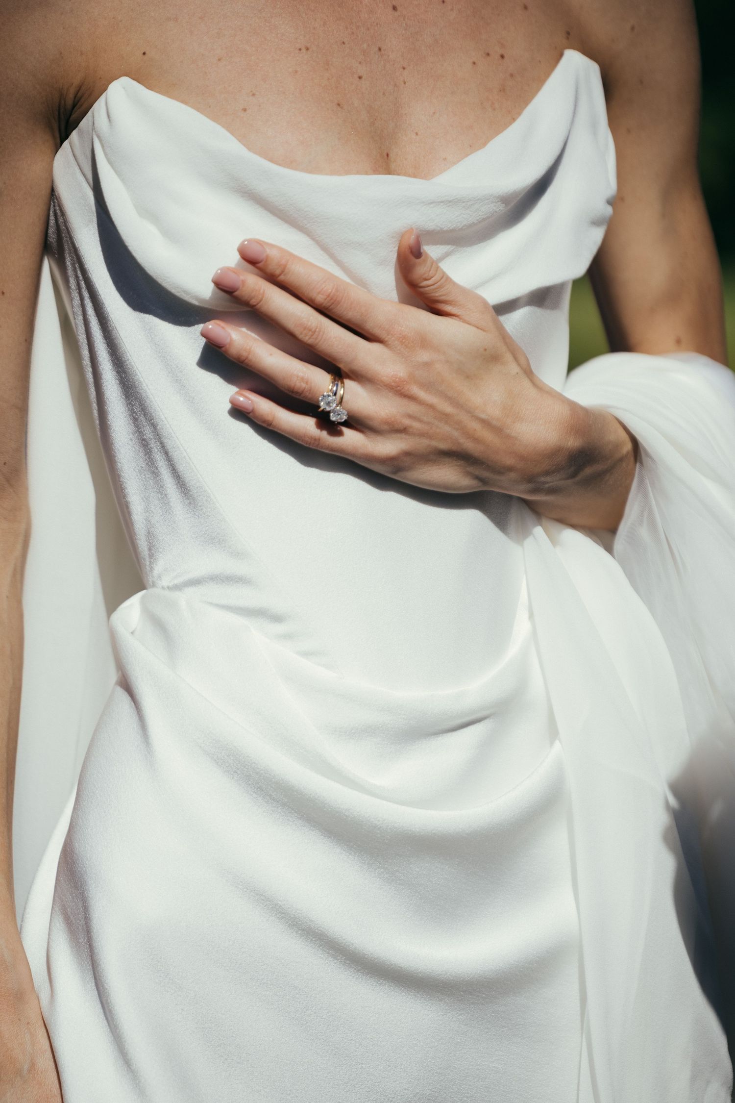 Close-up detail of white draped fabric with hands gently holding the material.
