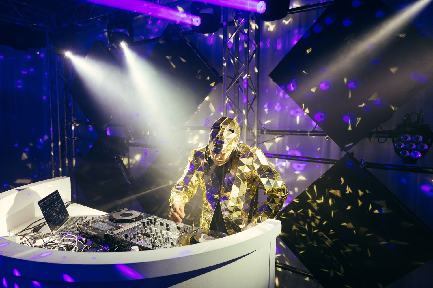 DJ booth at a nightclub with dramatic spotlights and golden confetti.