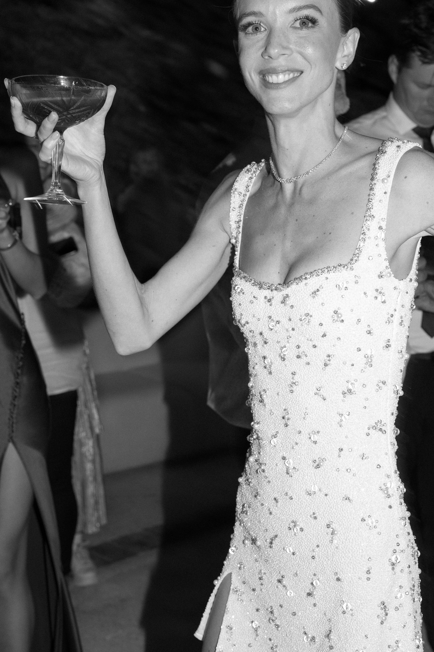 Woman in a sparkling white dress enjoying celebrations at an evening event.