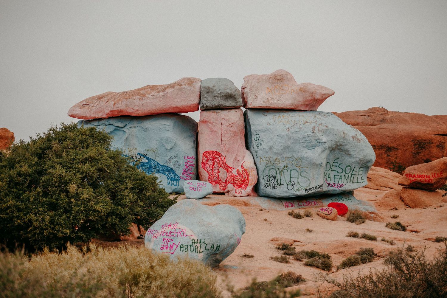 Vörös sziklaformációk a sivatagban, graffitivel és kék éggel a háttérben.