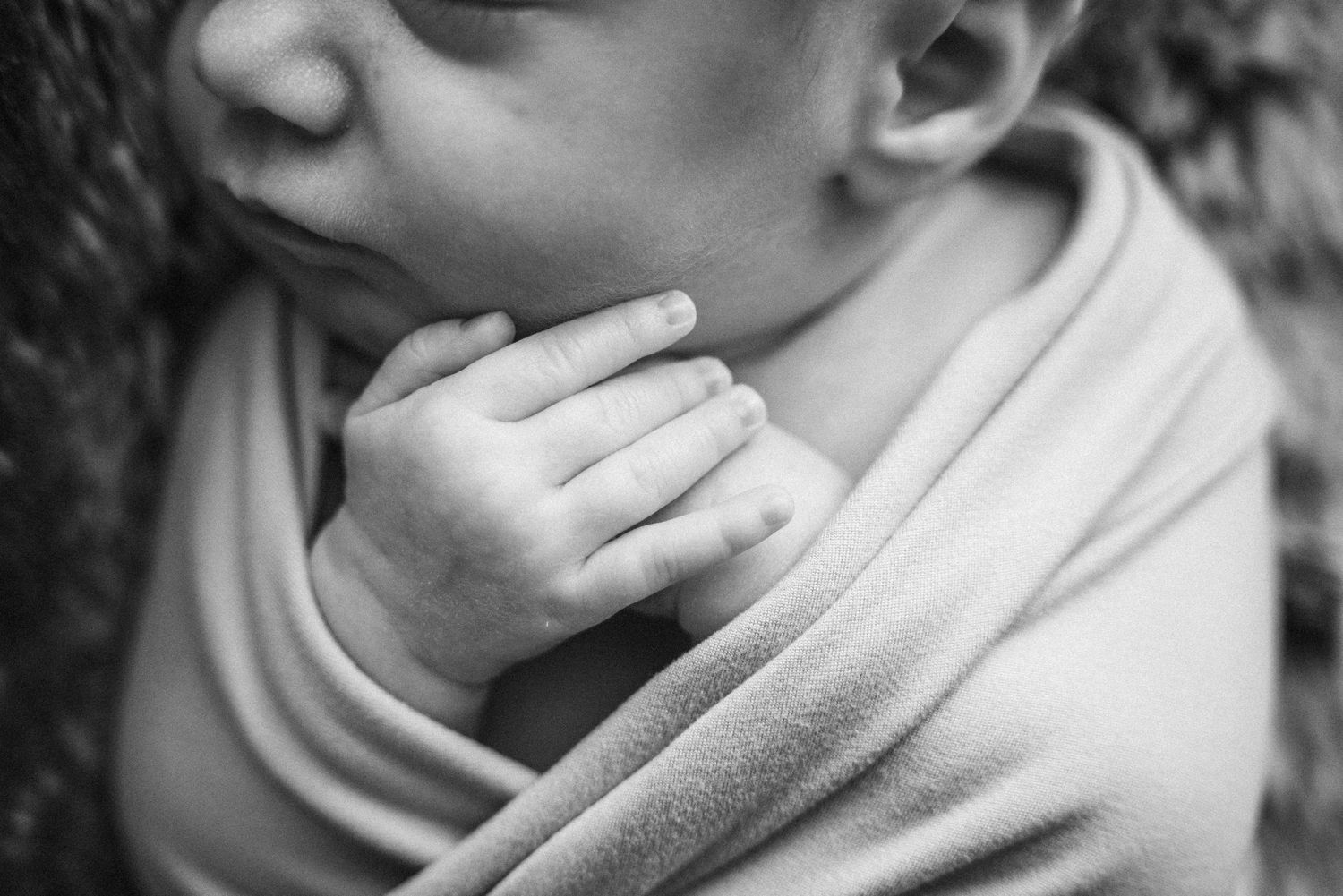 Close-up of sleeping newborn baby wrapped in soft fabric
