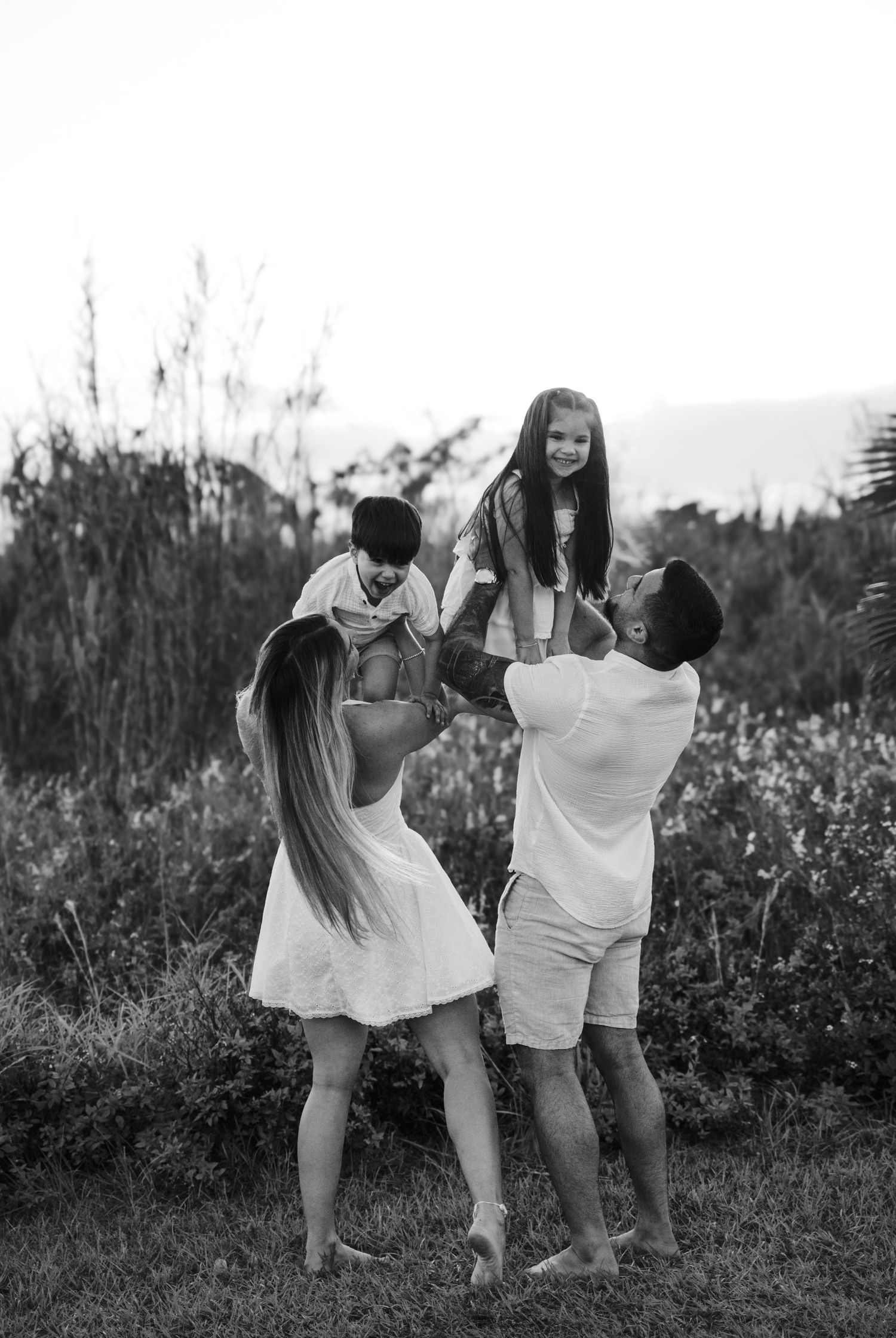 Black and white photo of family walking through tall grass outdoors