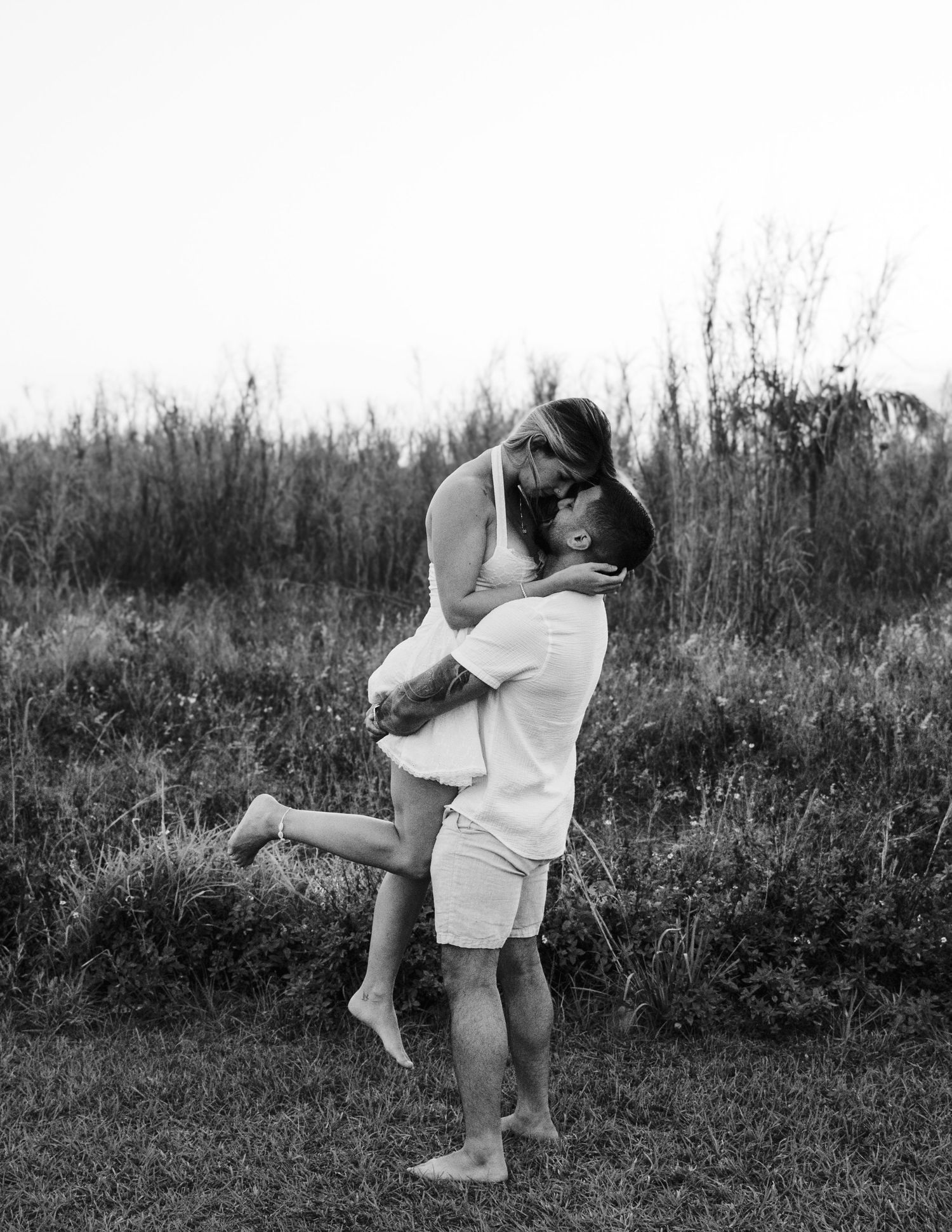Girl being carried by husband through grassy field captured in motion