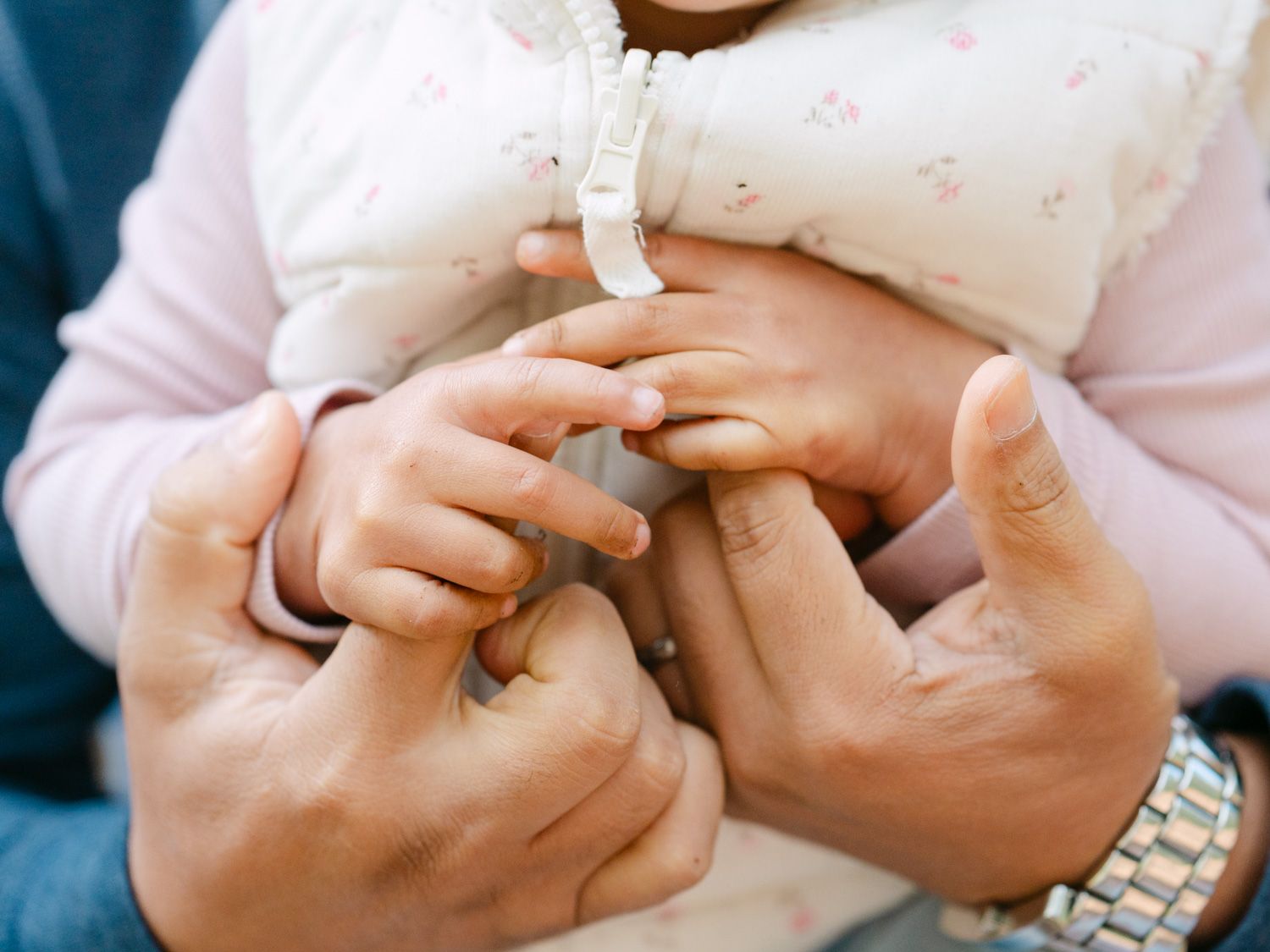 Close-up of parents holding their newborn baby's tiny hands, symbolizing love and family bonding.