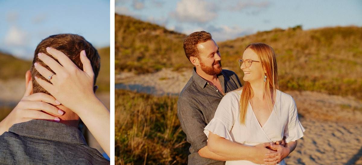 A couple shares a romantic moment on a sandy beach, with a close-up of an engagement ring on her hand.