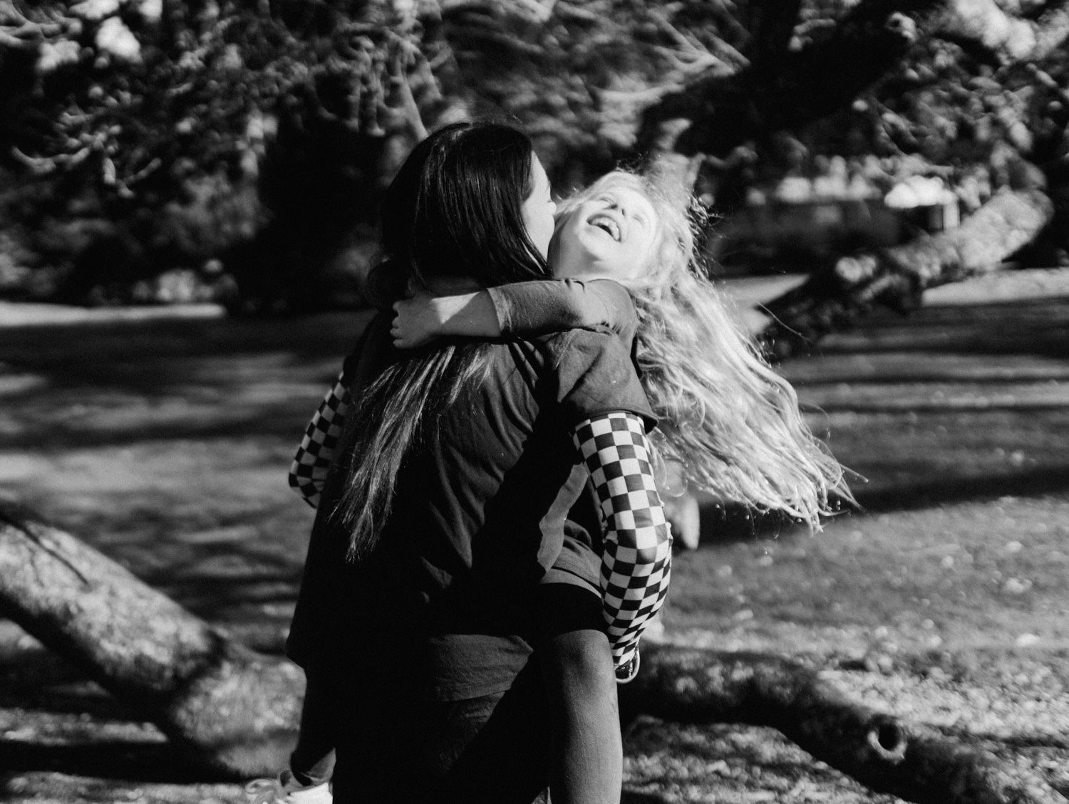 Black and white photo of a woman and young blonde girl sharing a warm embrace outdoors.