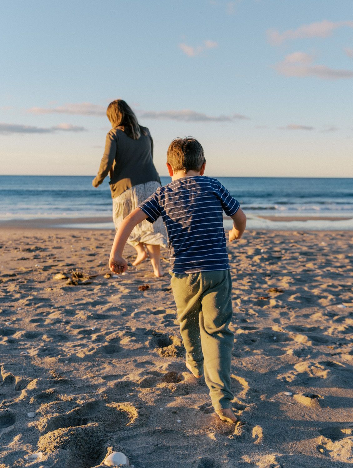 boy chasing his mum on the beach