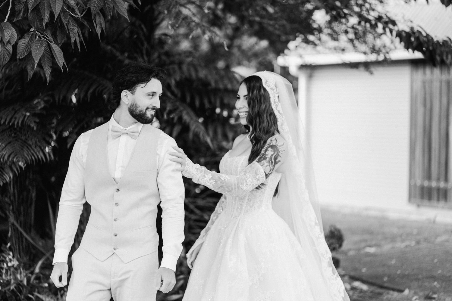 Black and white photo of bride and groom walking together outdoors on their wedding day.