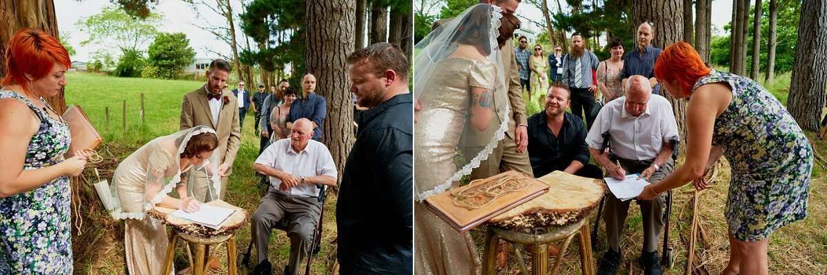 Wedding guests signing documents at a rustic outdoor reception surrounded by trees and natural decor.