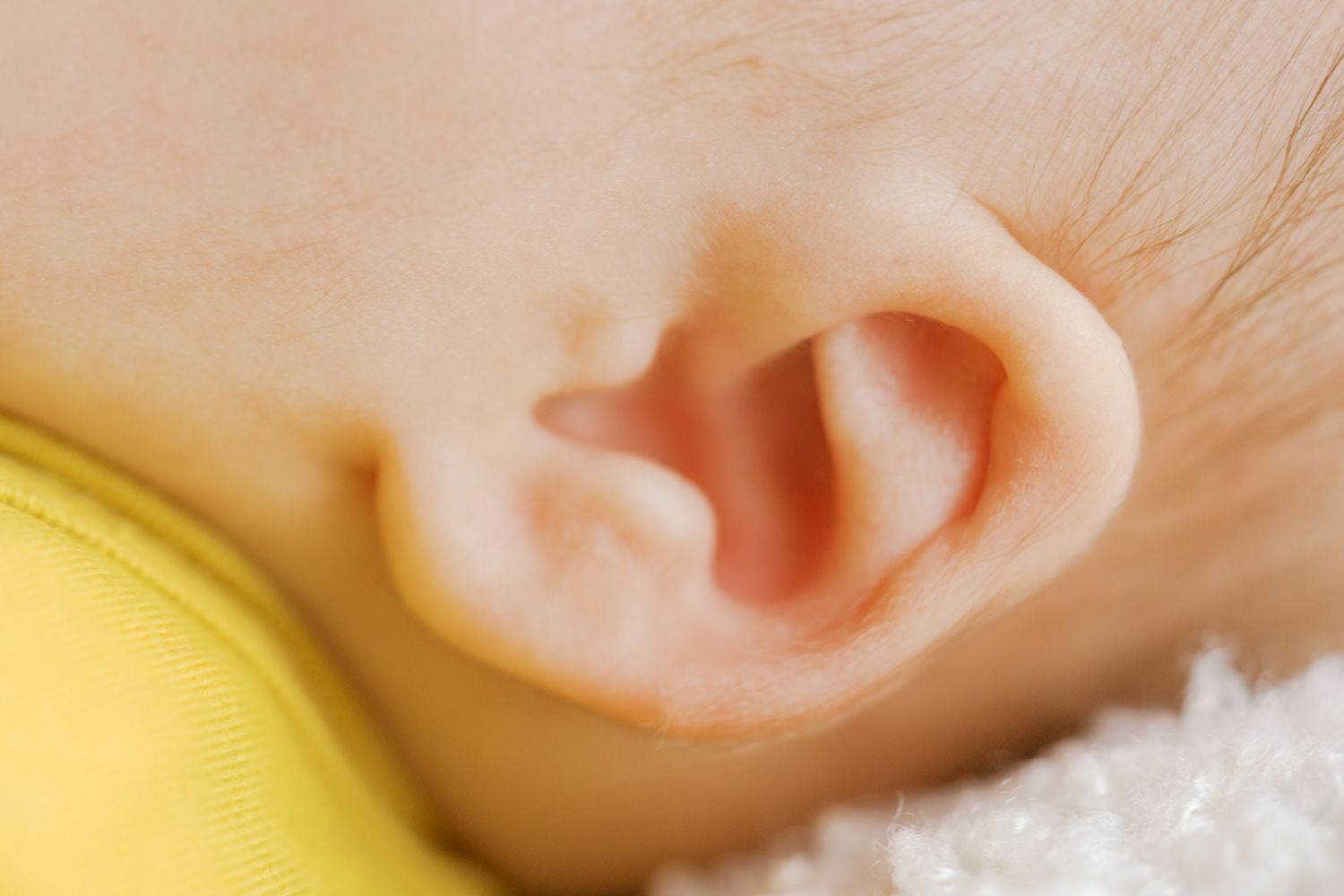 Close-up of a newborn baby's delicate ear, showcasing soft skin and tiny ear details.