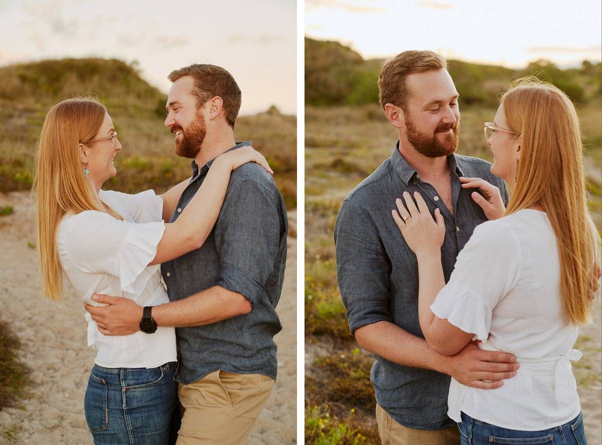 Couple embracing outdoors at golden hour, woman in white top and jeans, man in gray shirt, smiling at each other.