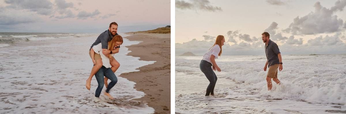 Couple playfully splashing in ocean waves on a sandy beach at sunset during a romantic engagement photo session.
