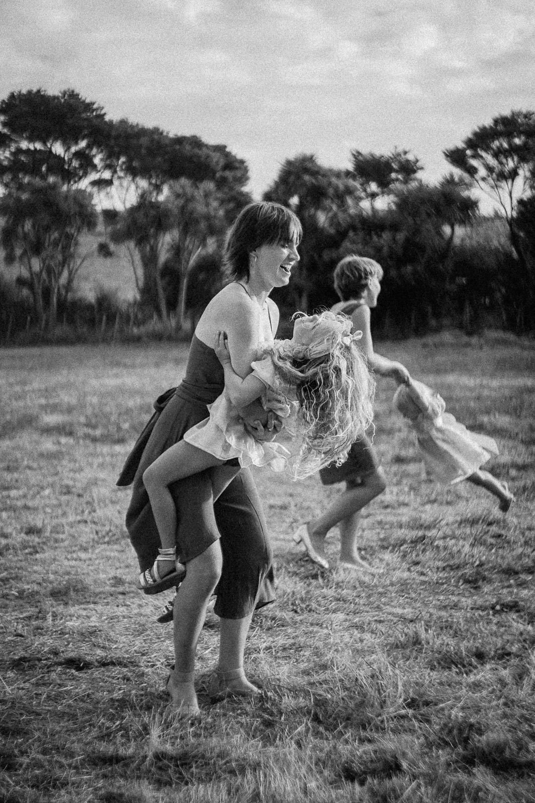 Black and white photo of children playing outdoors in a field, with trees in the background on a cloudy day.