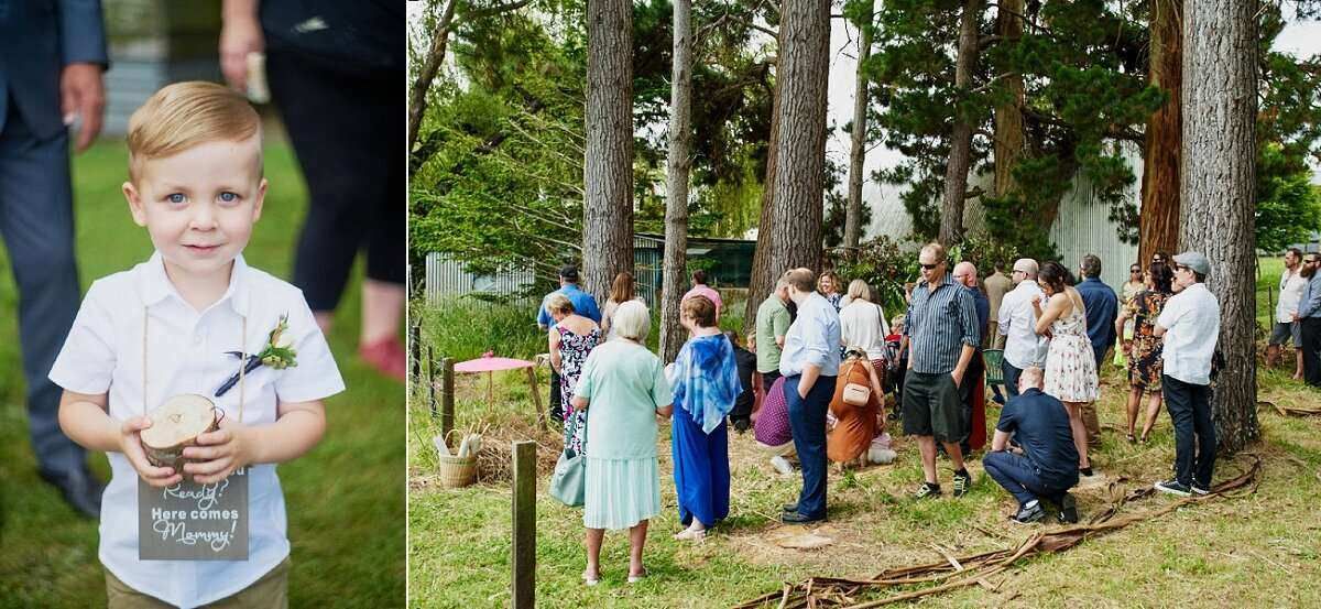 Young ring bearer in white shirt holding flowers at outdoor wedding ceremony with guests gathered among tall trees.