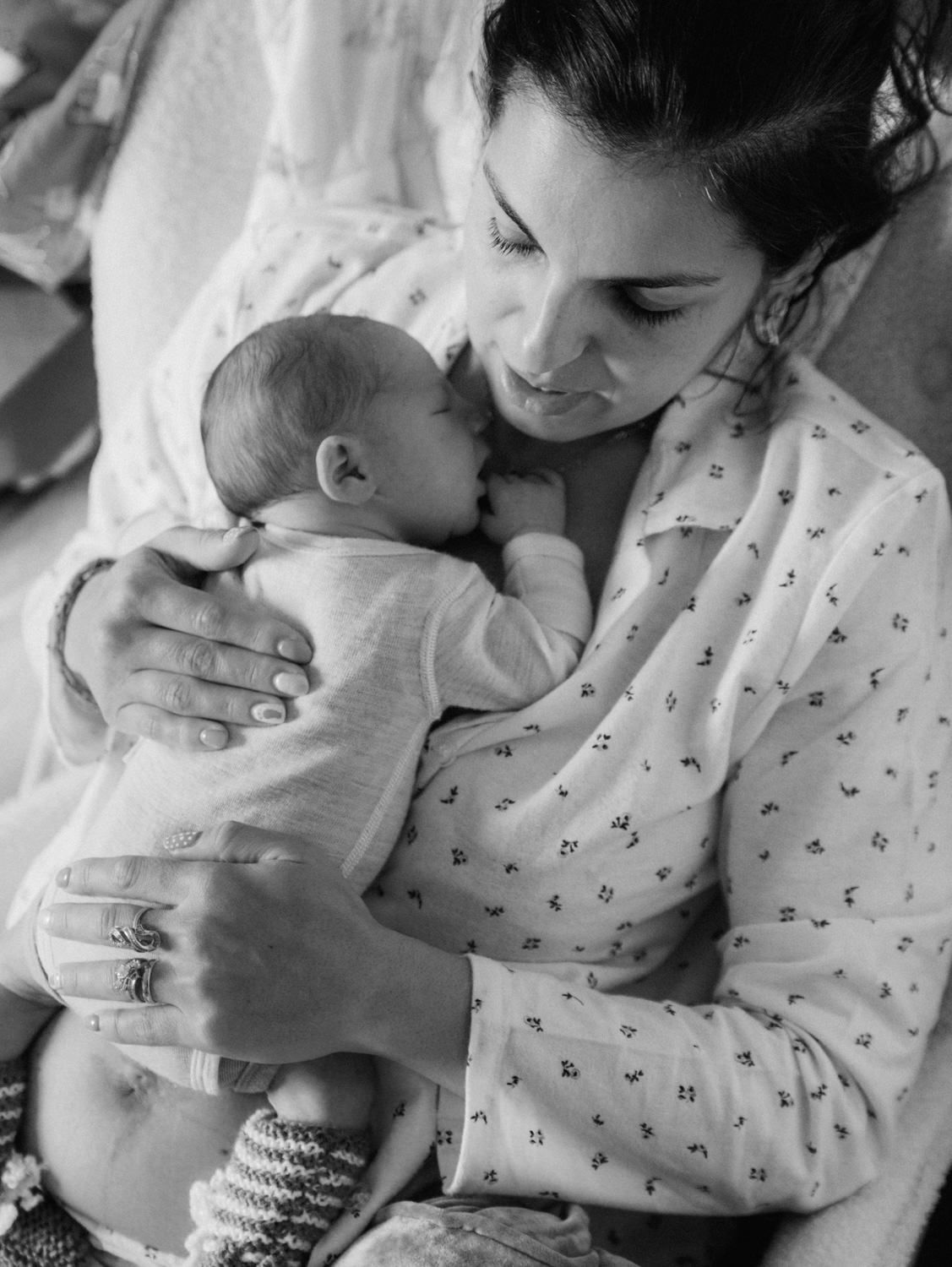 Black and white photo of a mother tenderly cradling her newborn baby, sharing a peaceful bonding moment.