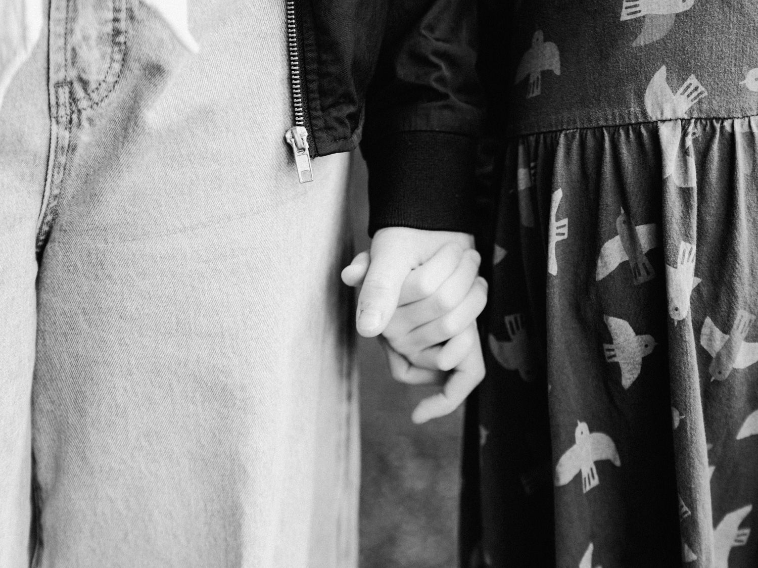 Black and white photo of a couple holding hands, wearing casual outfits, symbolizing love and togetherness.