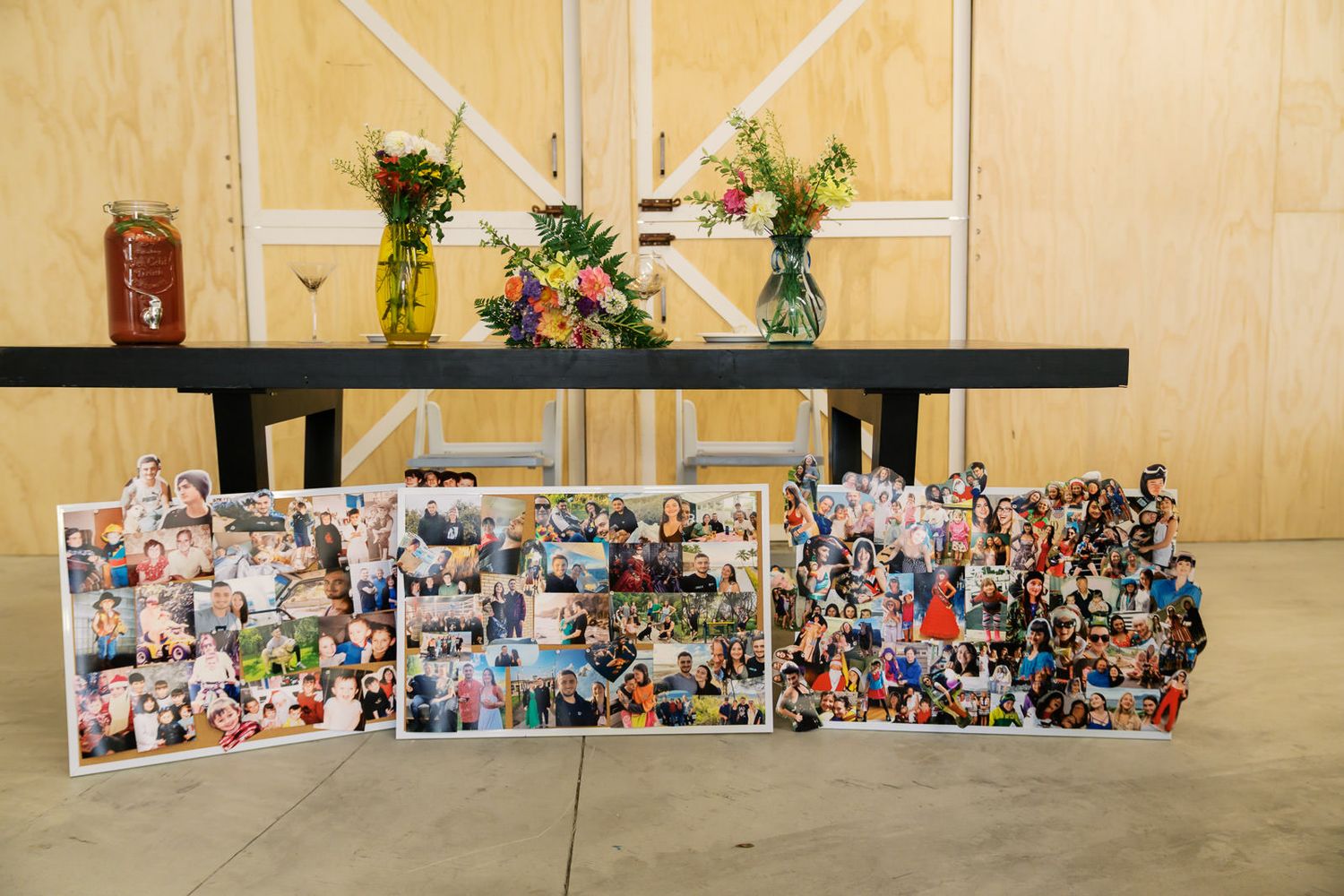 Photo collage display boards with colorful flower vases on a black table at an event venue.