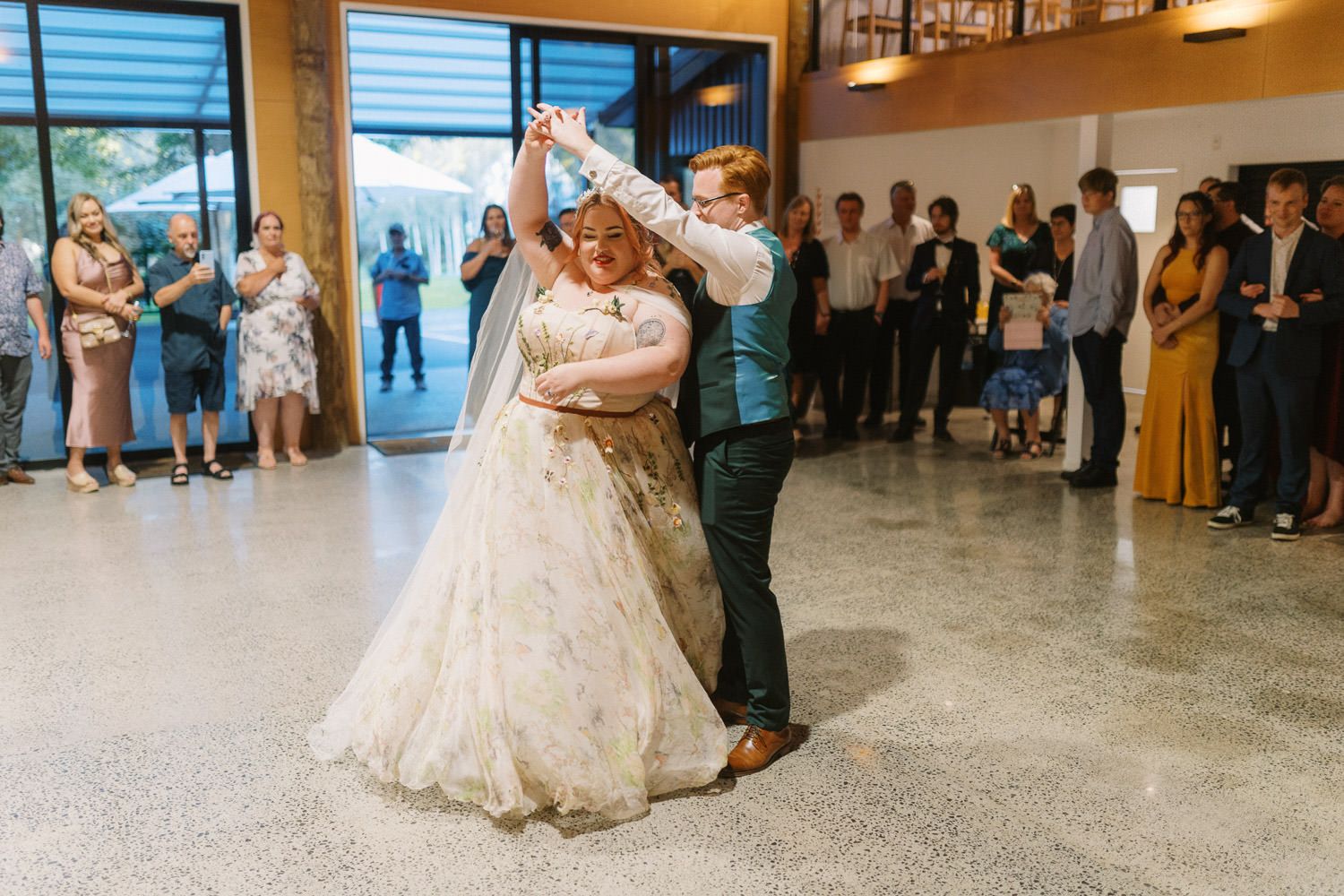 Bride and groom share their first dance at wedding reception while guests watch in elegant venue.