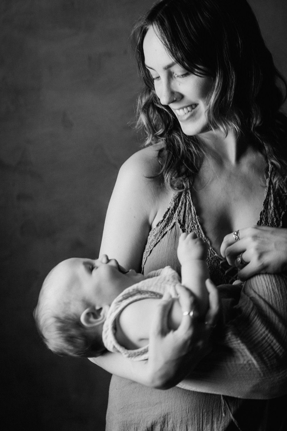 Black and white photo of a smiling mother tenderly holding her newborn baby in her arms.