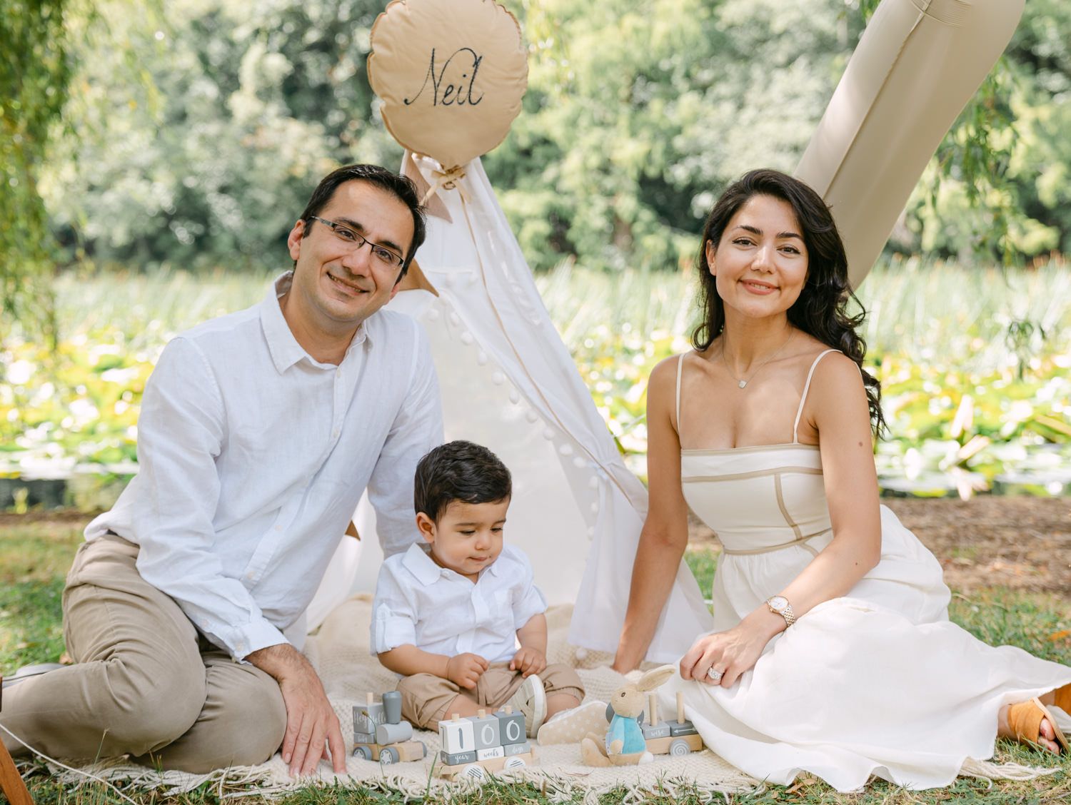Family photo session outdoors with parents and toddler son Neil celebrating his birthday with a teepee and balloon.