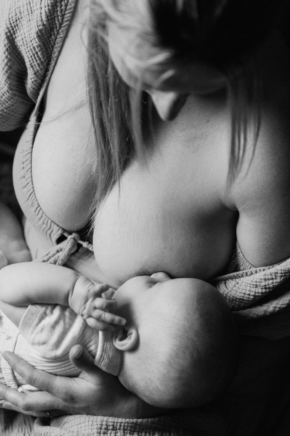 Black and white photo of a mother breastfeeding her newborn baby, a tender moment of maternal bonding.