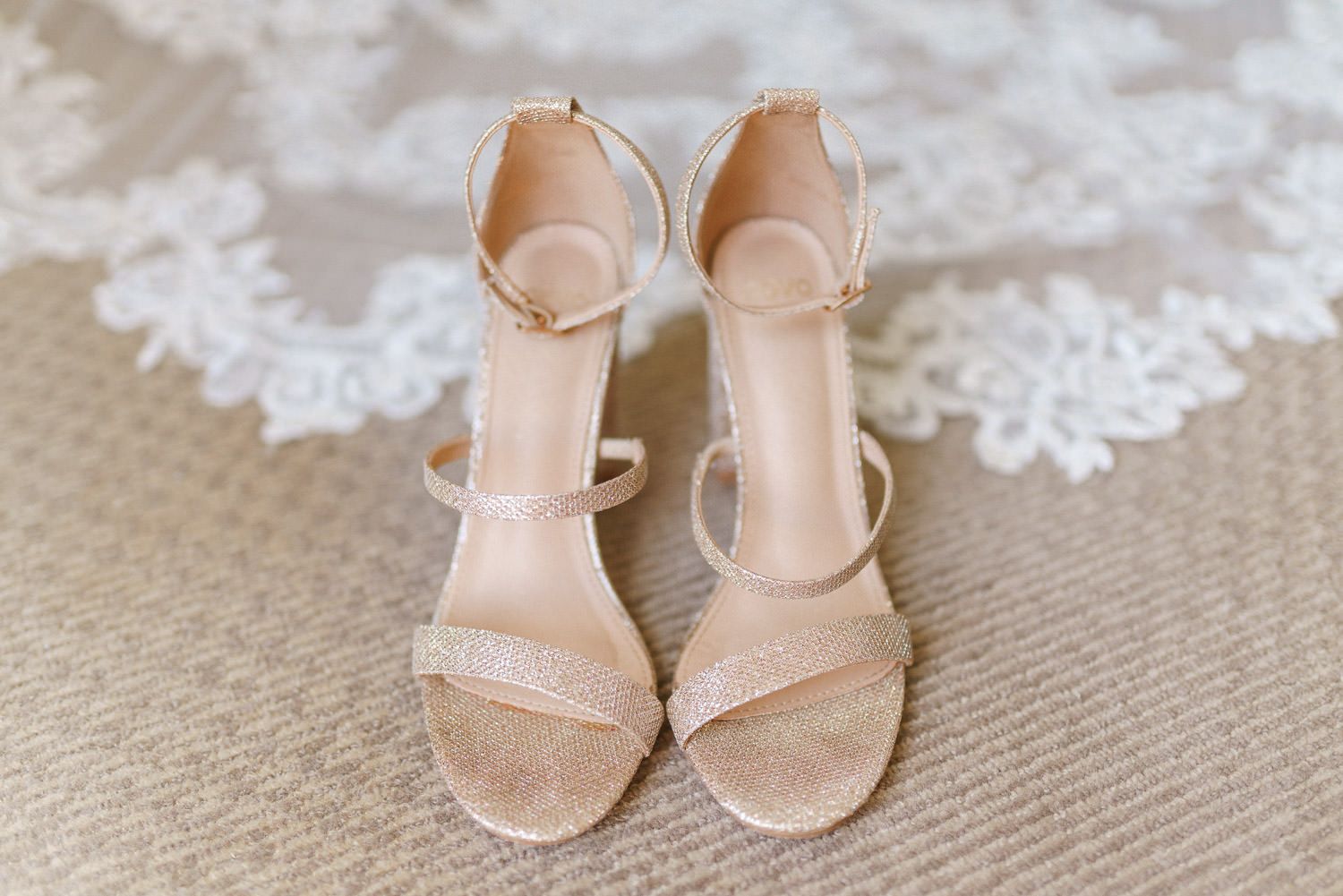 Elegant nude strappy block heel wedding sandals with ankle strap displayed on lace bridal veil backdrop.