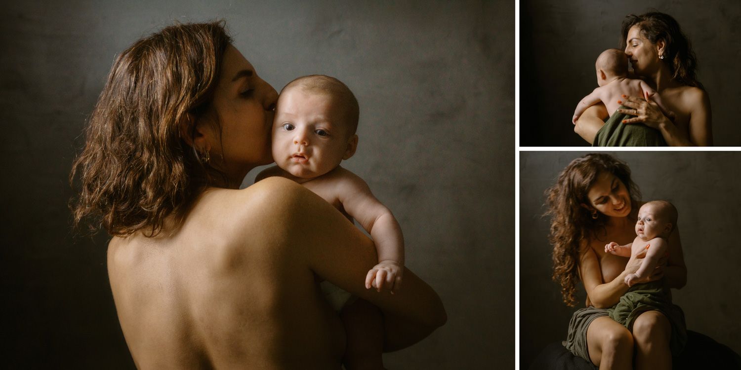 A mother tenderly kisses her newborn baby in a classic studio portrait series with warm, moody lighting.