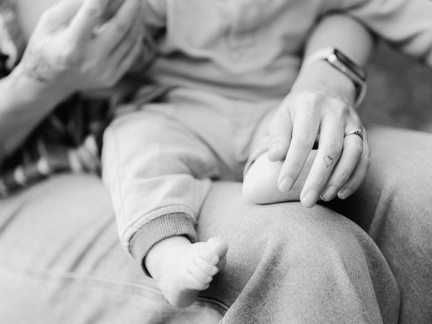 Black and white photo of a mother holding her newborn baby's tiny hand, a tender moment of new parenthood.
