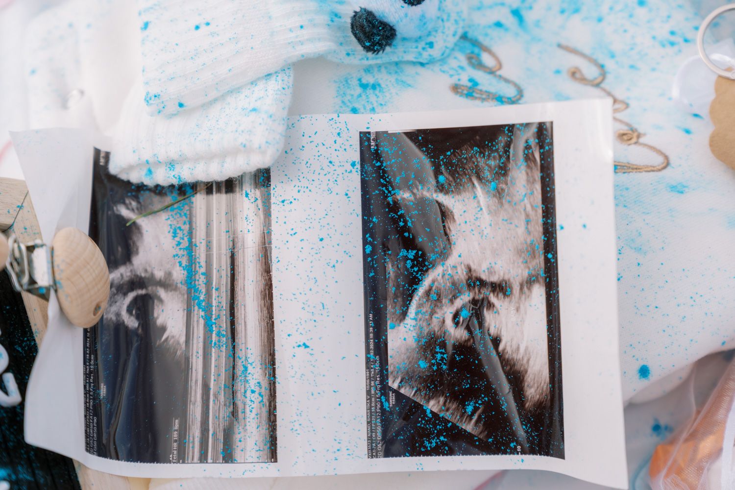 Open photo album with black and white portraits covered in blue glitter on a white surface with decorative items.