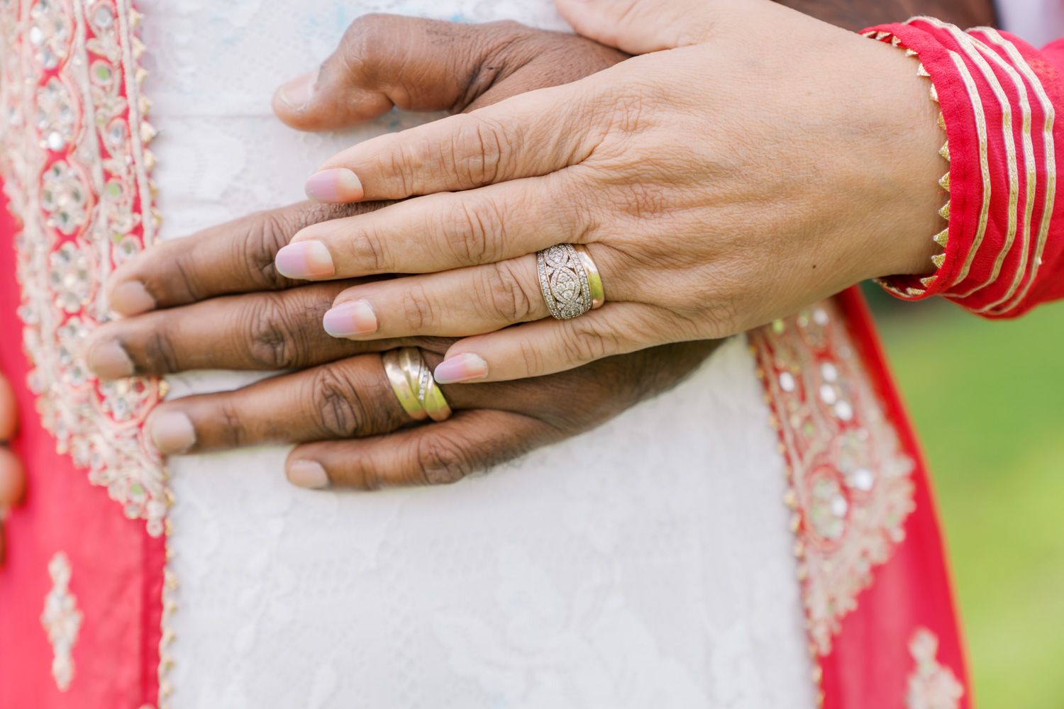 Close-up of bride and groom hands showing wedding rings, bangles, and henna at an Indian wedding ceremony.