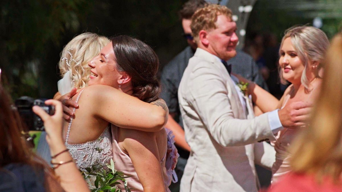 Joyful wedding guests hugging and celebrating after outdoor ceremony with bride and groom nearby.