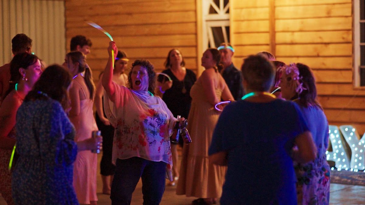 Group of people dancing at an outdoor evening party with colorful neon lights illuminating the celebration.