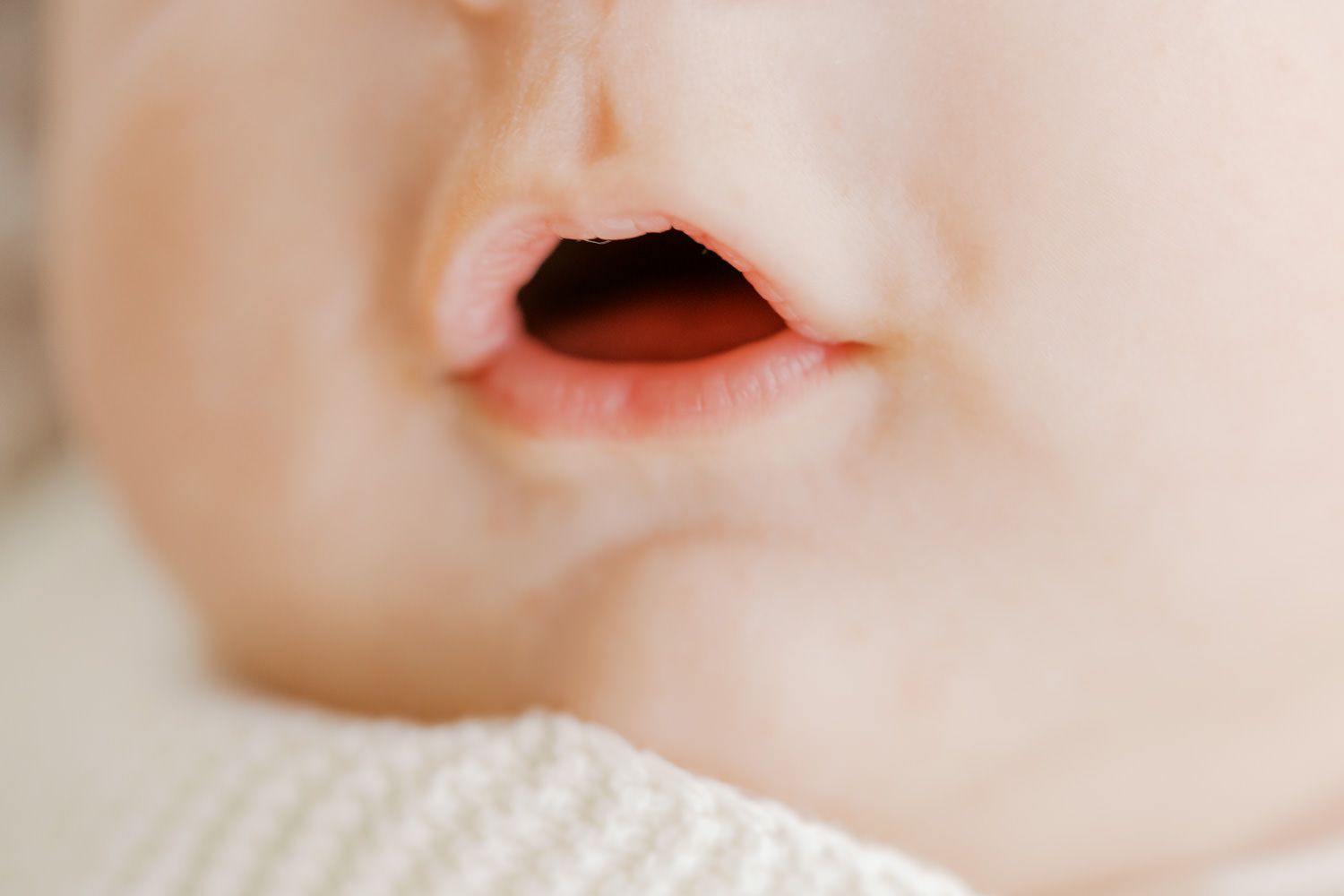 Close-up of a sleeping baby's nose and slightly open mouth with soft pink lips.