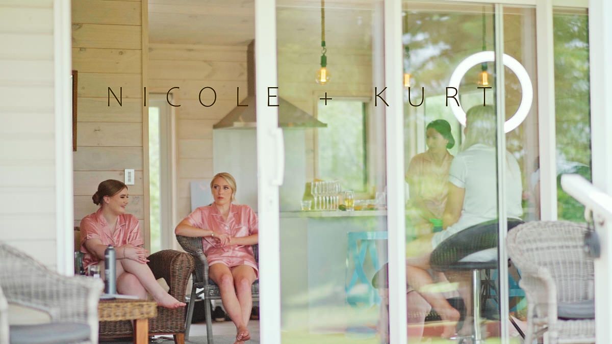 Nicole and Kurt wedding couple with bridesmaids relaxing on a modern porch with glass doors and pendant lighting.
