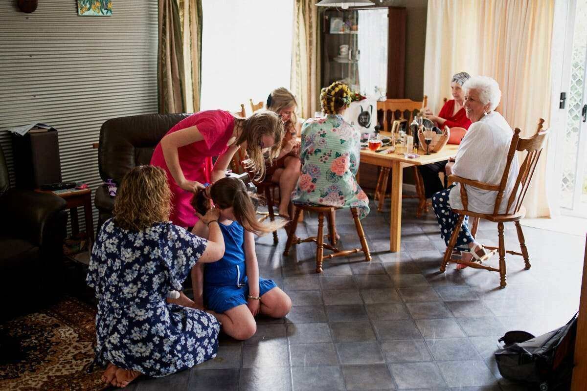 Multi-generational family gathering indoors, with women and children socializing around a dining table in a cozy living room.